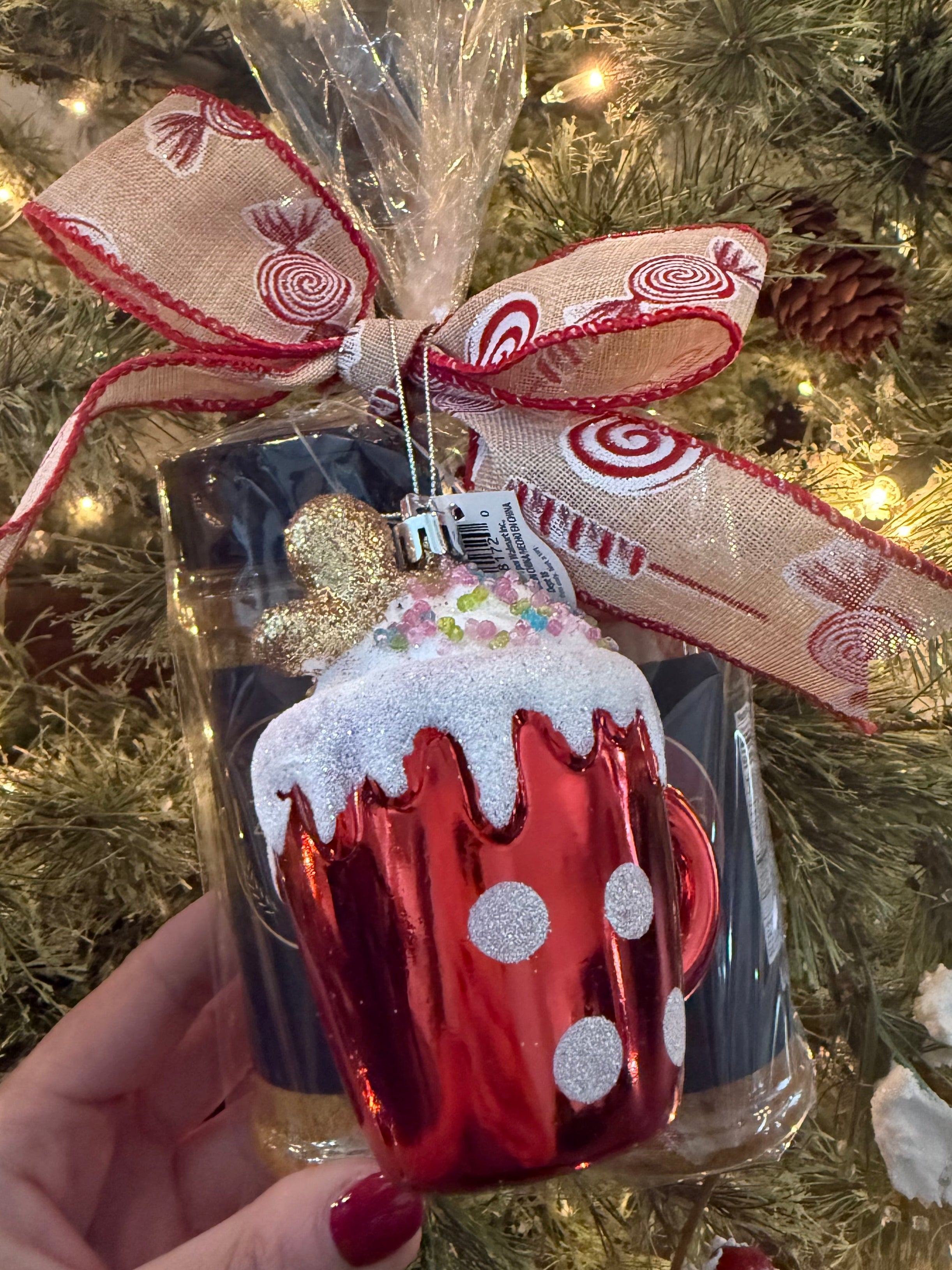 Izzo’s Season holiday gift set with hot cocoa ornament and candy-themed ribbon under Christmas tree lights.